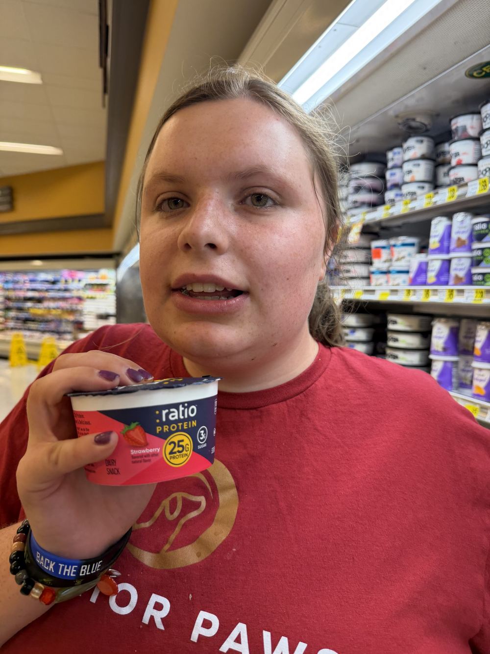 A woman holding a yogurt container in a grocery store
