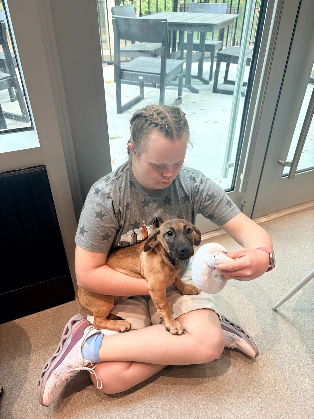 A woman seated on the floor holding a puppy
