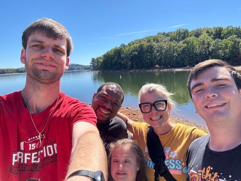 A group smiling together beside a lake