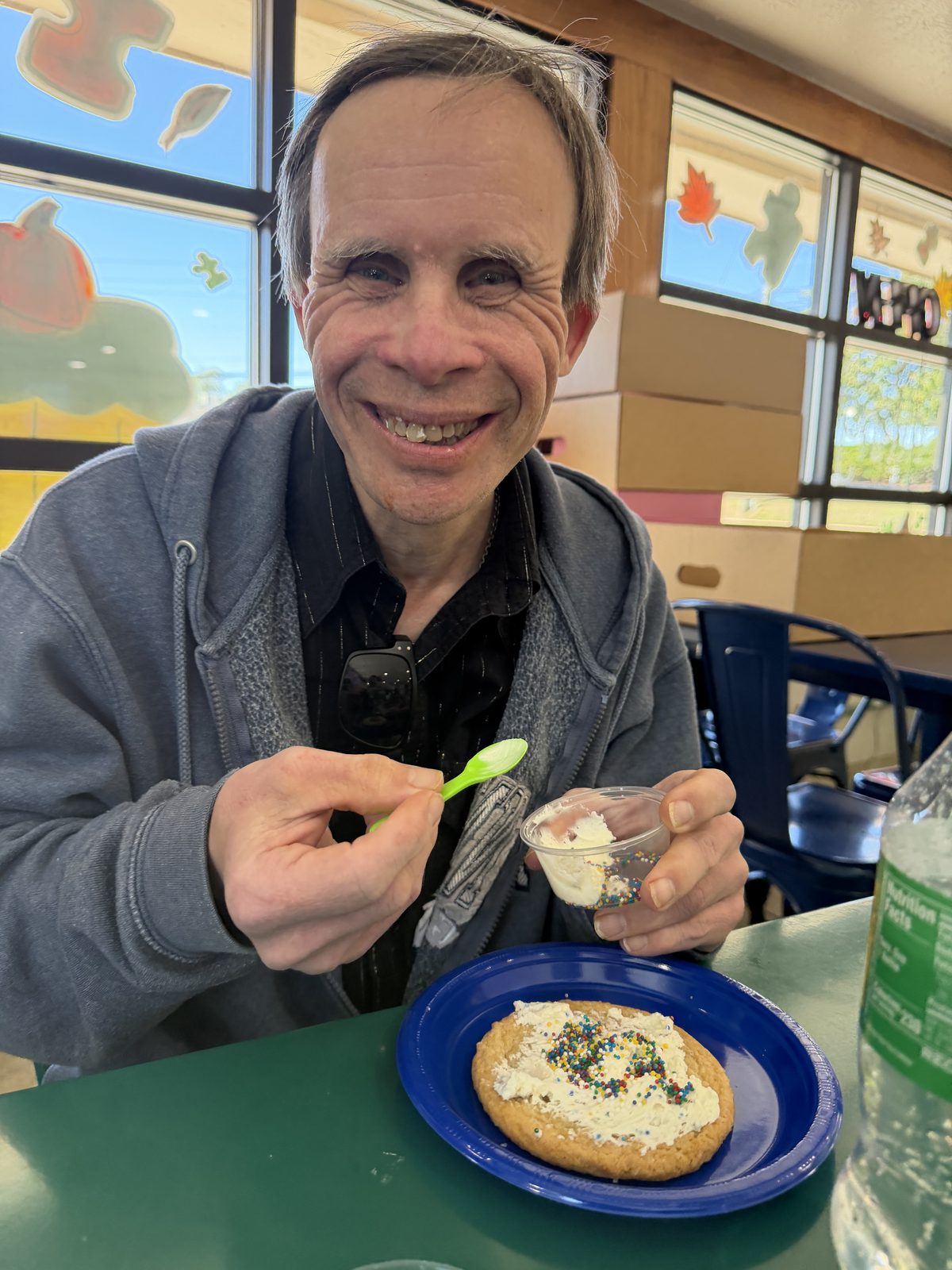 A smiling man holding a spoon and dessert at a table