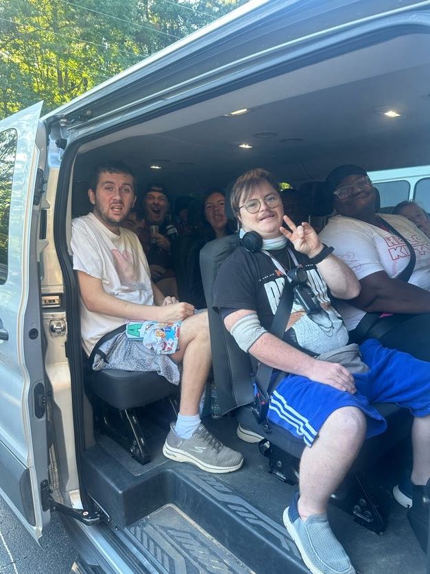 A group seated together inside a van with its side door open